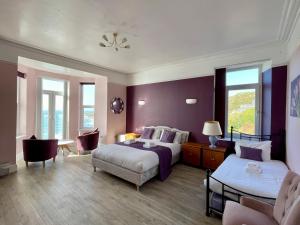 a bedroom with purple walls and a bed and a couch at Lundy House Hotel in Woolacombe