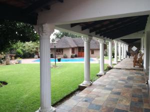 an outdoor pavilion with white columns and a yard at Magnolia Guesthouse & coffeeshop in Vaalpark