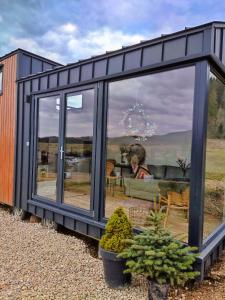 una casa negra con una gran ventana con una persona en el fondo en Domek w górach Tiny House Forest Jacuzzi/widoki, en Lipnica Wielka