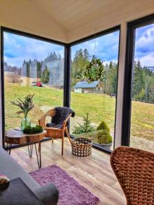 a screened in porch with a view of a field at Domek w górach Tiny House Forest Jacuzzi/widoki in Lipnica Wielka