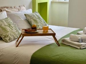 a tray of food and a glass of orange juice on a bed at Nênê House - Casa de Praia by Férias em Figueira in Figueira da Foz