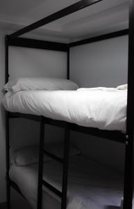 Litera negra con sábanas y almohadas blancas en Be Happy Hostel, en Nerja