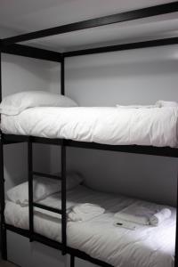 a black bunk bed with two white pillows on it at Be Happy Hostel in Nerja