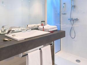 a bathroom with a sink and a shower with towels at Ibis Styles Menton Centre in Menton
