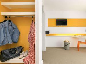 a room with yellow walls and a closet with shoes at Ibis Styles Menton Centre in Menton