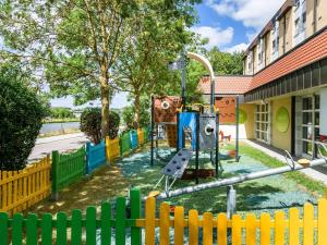 un parque infantil frente a un edificio con una valla en Ibis Styles Regensburg en Regensburg