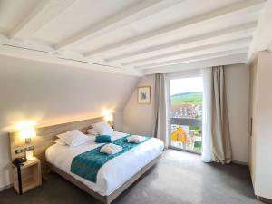 a bedroom with a bed and a large window at Best Western Hotel & SPA Le Schoenenbourg in Riquewihr