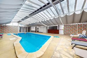 a large swimming pool in a large building at Chambre dans un manoir au bord de l'Yonne près de Sens in Villeperrot