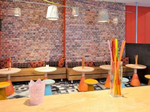 um quarto com mesas e cadeiras e uma parede de tijolos em ibis Styles Lille Centre Grand Place em Lille