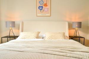 a bedroom with a large white bed with two lamps at MILPAU Bottrop 2 - Modernes und zentrales Premium-Apartment für 4 Personen mit Queensize-Bett und Einzelbetten - Netflix, Nespresso und Smart-TV in Bottrop