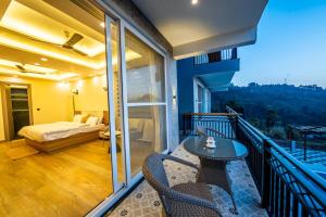 een balkon met een bed en een tafel en stoelen bij sunset villa in Nainital