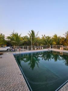 a large swimming pool in a resort with palm trees at Amaravathi farm stay in Arakkonam