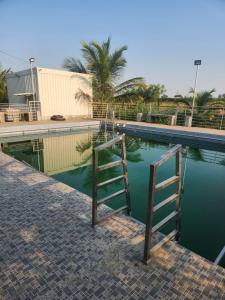 a swimming pool with a ladder in the water at Amaravathi farm stay in Arakkonam