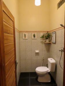 a small bathroom with a toilet and a door at Blue Waves Balangan Homestay in Uluwatu