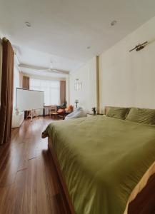 a bedroom with a large green bed and a screen at HeHe Homestay Hanoi in Hanoi