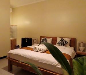 1 dormitorio con 1 cama con sábanas y almohadas blancas en Blue Waves Balangan Homestay, en Uluwatu
