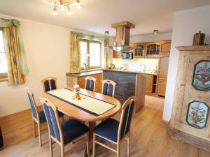 eine Küche und ein Esszimmer mit einem Holztisch und Stühlen in der Unterkunft Cosy holiday flat in a farmhouse in Taxenbach