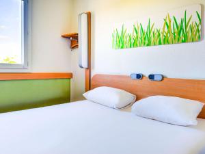 a bedroom with two beds with blue glasses on the headboard at Ibis Budget Orly Chevilly Tram 7 in Chevilly-Larue
