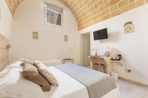um quarto branco com uma cama e uma parede de tijolos em Clara Domus em Gallipoli