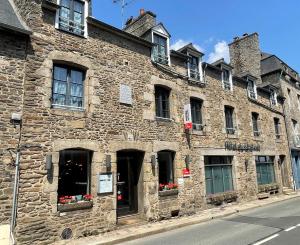 Un antiguo edificio de piedra con flores en las ventanas. en Hôtel du Château Dinan - Originals Boutique, en Dinan