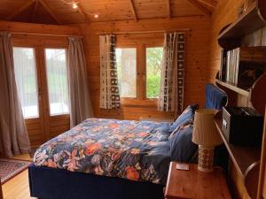 ein Schlafzimmer mit einem Bett in einem Blockhaus in der Unterkunft Exclusive 1 or 2 Bedroom Apartment with Summer House and Hot Tub in Daventry