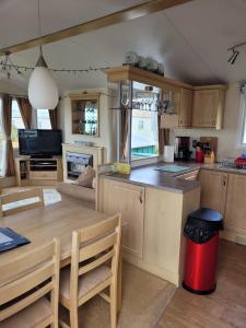 a kitchen and living room with a table and a counter at Cosy caravan Sunbeach in Llwyngwril