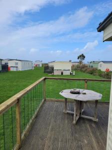 a picnic table on a deck with a field at Cosy caravan Sunbeach in Llwyngwril