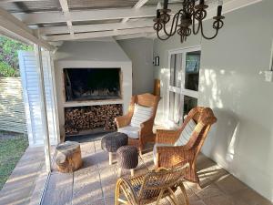 a porch with wicker chairs and a fireplace at Onrus Cottage in Hermanus
