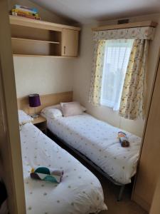 two twin beds in a room with a window at Cosy caravan Sunbeach in Llwyngwril