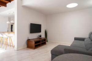 a living room with a couch and a tv on a wall at Lanzahost Casa Sunny Seafront in Costa Teguise