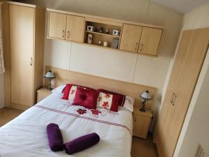 a bedroom with a bed with purple pillows on it at Cosy caravan Sunbeach in Llwyngwril