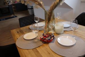 a wooden table with plates and wine glasses on it at Hirsch24- 4 Personen Apartment in Lippstadt