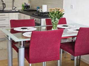 a dining room table with red chairs and a vase of flowers at Apartman Britt in Zagreb