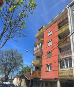 a red building with balconies on a street at Apartman Nini in Kraljevo