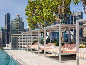 - un ensemble de chaises longues installées à côté de la piscine dans l'établissement Mondrian Singapore Duxton, à Singapour