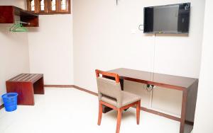 a desk with a chair and a tv on a wall at Comfort Inn Mbezi Beach in Dar es Salaam