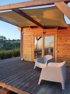 eine Holzhütte mit einer Terrasse mit zwei weißen Stühlen in der Unterkunft Petirrojo in Vejer de la Frontera