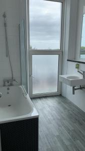 baño con 2 lavabos, bañera y ventana en Citrus Hotel Eastbourne by Compass Hospitality, en Eastbourne