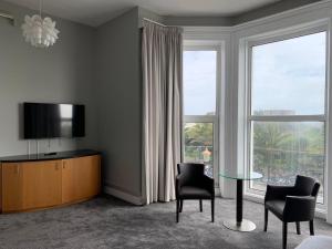 a living room with a television and a table and chairs at Citrus Hotel Eastbourne by Compass Hospitality in Eastbourne