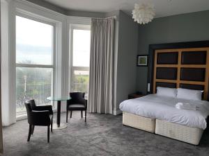 イーストボーンにあるCitrus Hotel Eastbourne by Compass Hospitalityのベッドルーム1室(ベッド1台、テーブル、椅子付)