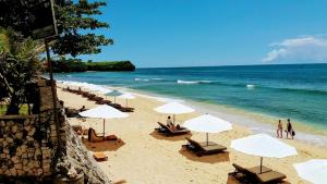 una playa con sillas y sombrillas y el océano en Blue Waves Balangan Homestay, en Uluwatu
