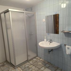ein Bad mit einer Dusche und einem Waschbecken in der Unterkunft Pensión Rural para Peregrinos "AREAL" in Padrón