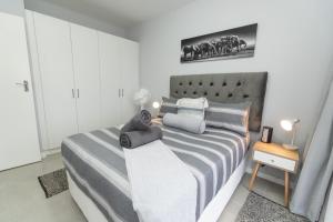 una camera da letto con un letto con copriletto grigio e bianco. di The Cozy Traveller a Gqeberha