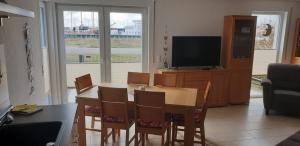 Haus am Leuchtfeuer A في بيناموندا: غرفة معيشة مع طاولة وكراسي وتلفزيون