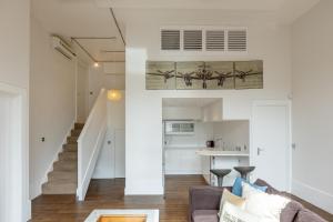uma sala de estar com um sofá e uma escada em Gorgeous loft style 3BR apt, Battersea em Londres