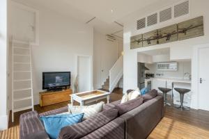 ein Wohnzimmer mit einem Sofa und einem TV in der Unterkunft Gorgeous loft style 3BR apt, Battersea in London