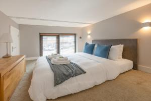 um quarto grande com uma cama grande e almofadas azuis em Gorgeous loft style 3BR apt, Battersea em Londres