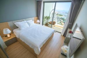 una camera da letto con un letto bianco e una grande finestra di Homestay citadines a Ha Long Altre 68 foto