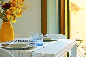 a table with plates and glasses and a vase with flowers at Martha's in Follonica