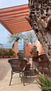 a patio with chairs and awning and a tree at Casa sul mare in Procchio